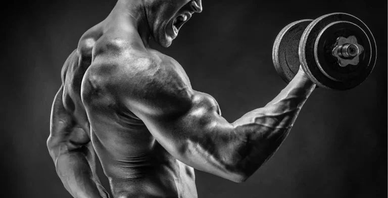 A muscular bodybuilder performing an intense dumbbell curl, showcasing the benefits of TRT for bodybuilders explained in muscle growth and strength enhancement.