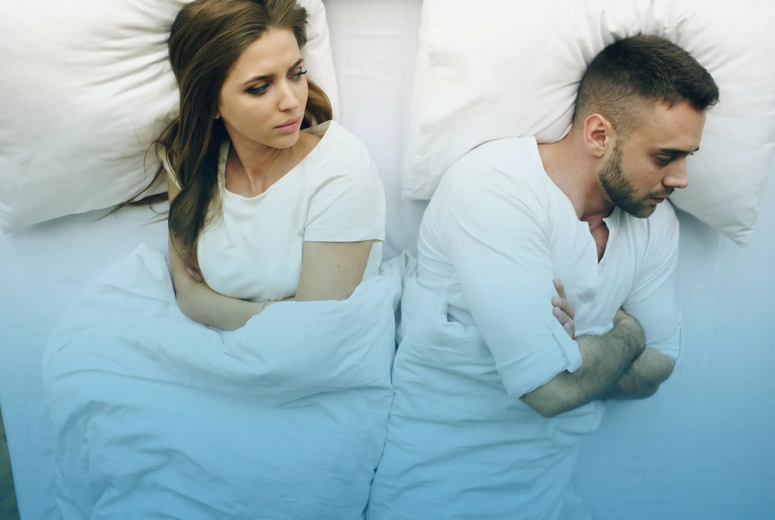 Unhappy couple lying back-to-back in bed showing relationship strain caused by low testosterone and reduced sex drive in the USA