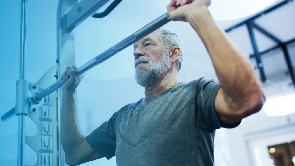 Older man lifting weights in a gym to support strength, healthy aging, and testosterone levels after 60