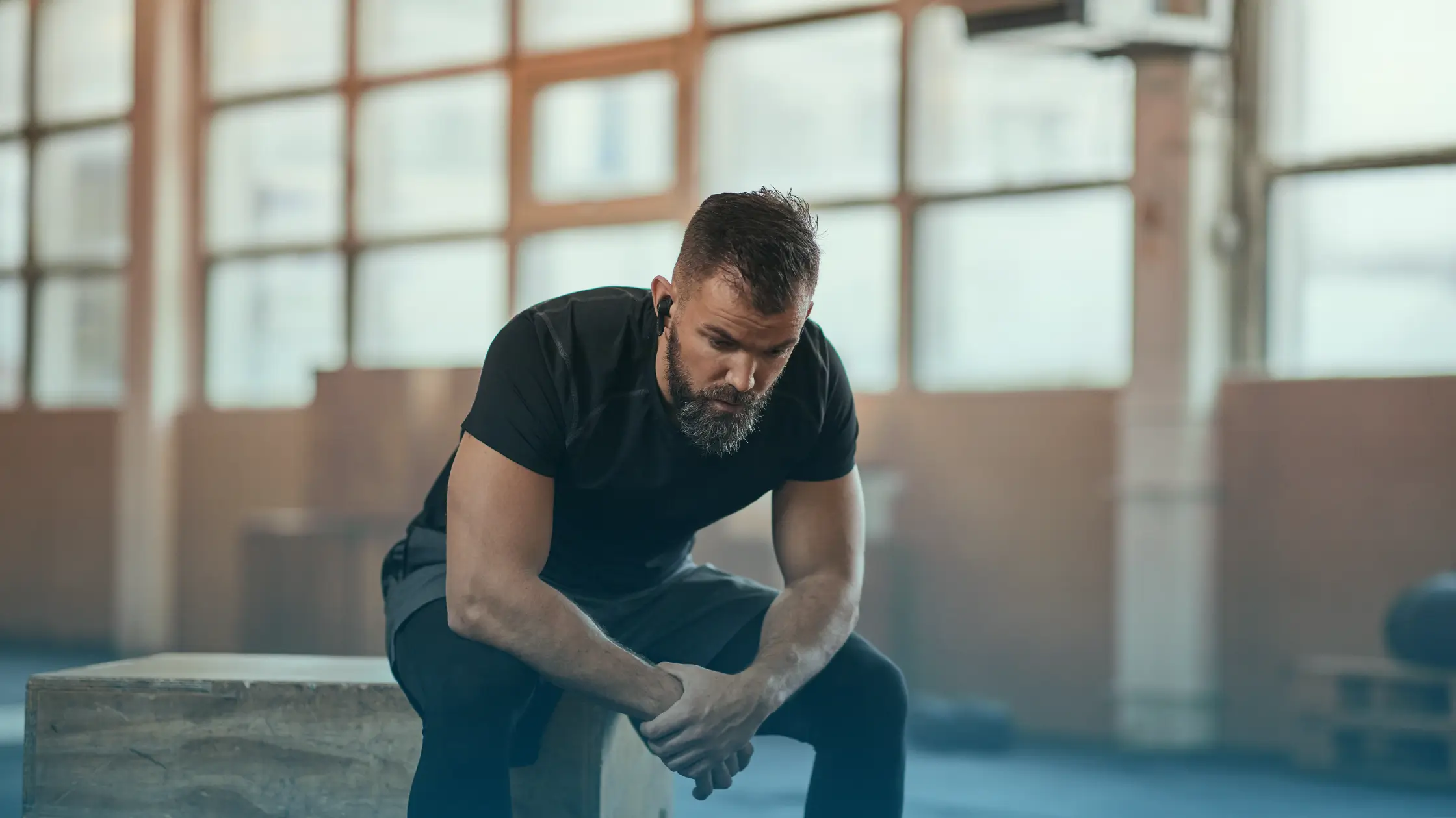 Tired man sitting in a gym showing common signs of low testosterone and fatigue in men across the USA