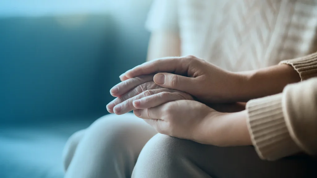One person holding another person’s hand in comfort and emotional support during depression and hormone imbalance treatment