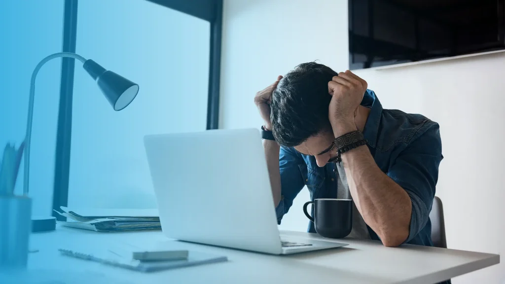 Exhausted man at desk showing signs of hormonal imbalance and fatigue that may require hormone replacement therapy in the USA