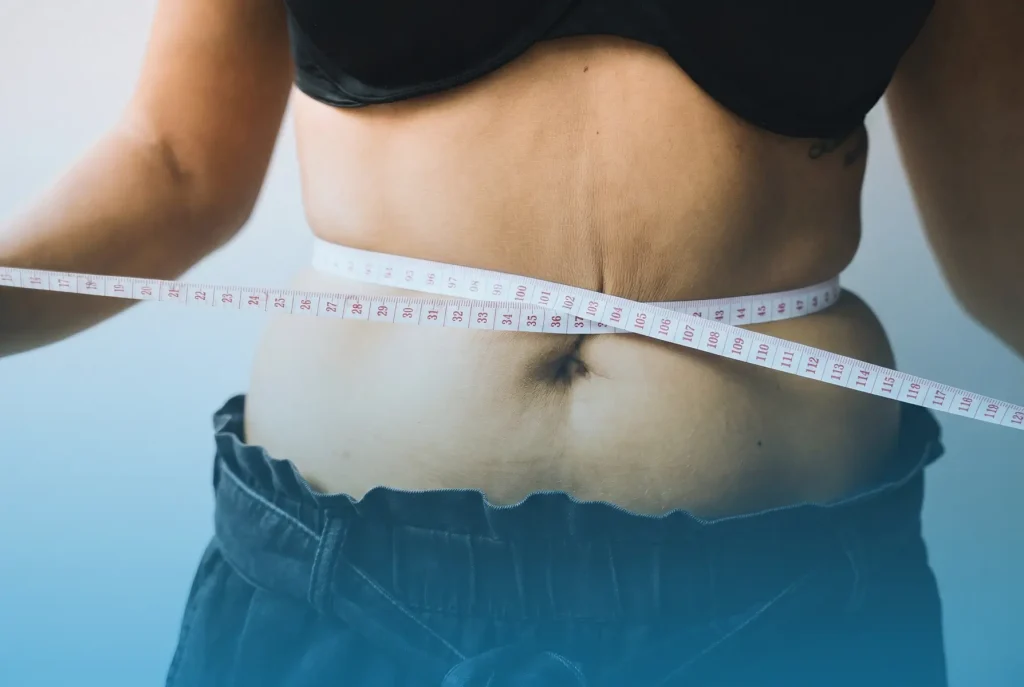 Woman measuring her waist with a tape representing midlife weight gain and hormonal belly fat in women
